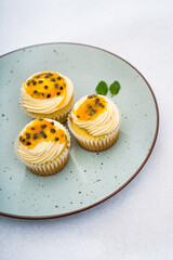 passion fruit cupcakes decorated by a piping bag white cream on a dish and a marble background