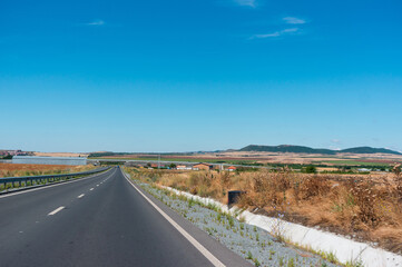By car on the highway past the fields. Color photo