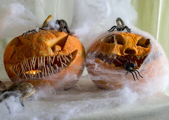 carved pumpkin with a scary smile, spiders, white cobweb background, decoration and holiday...