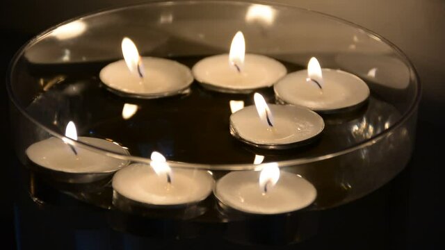 Close up of several floating candles in a glass of water. Beautiful candle light. Atmosphere of romance and love. 