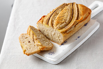 homemade banana bread on a wooden board on a table with a tablecloth