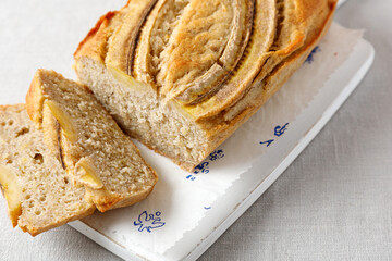 homemade banana bread on a wooden board on a table with a tablecloth