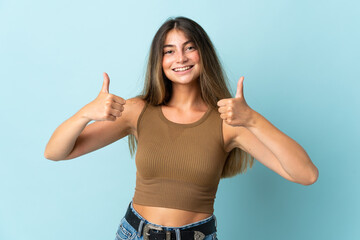 Young caucasian woman isolated on blue background giving a thumbs up gesture