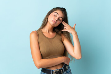 Young caucasian woman isolated on blue background with problems making suicide gesture