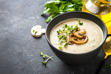 Mushroom Soup in black bowl on dark stone table.