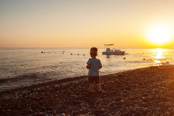 A child on the seashore watching the sunset. Rocky beach, vacation vacation.