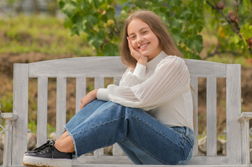 Obraz premium cheerful kid sitting on bench in park, childhood
