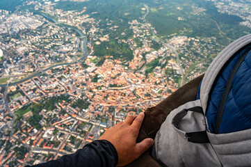 Holding hand on handrail of flying hot air balloon basket during the scenic flight above famous Old Town of Vilnius capital of Lithuania
