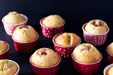 Delicious sweet muffins with different fillings: banana, strawberry, apple on black background.