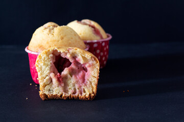 Muffins with cherries on a black background. Cut in half.