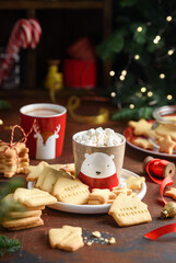 Children's сhristmas shortbread cookies with cocoa mug on a wooden table. Festive cookies with the...