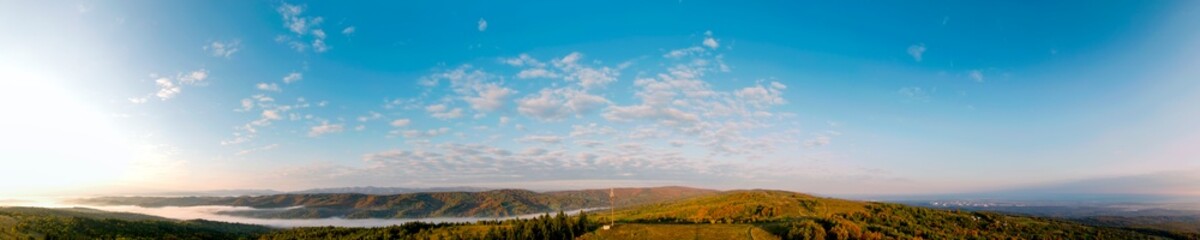 Beautiful autumn panorama of yellow and red trees against the background of big mountains