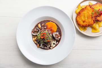 Black ceviche with shell, very typical in Peru. on white plate.
