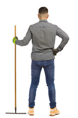 Rear view of standing gardener with a rake. Full length isolated.
