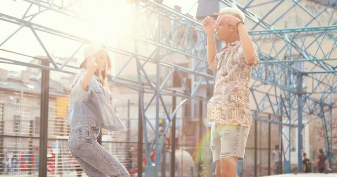 Move your body. Portrait shot of handsome multiracial man and his caucasian girlfriend dancing at the street of town center at sunlight. Students, urban life concept