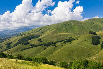 Fototapeta na wymiar Green mountains of Ossetia. Cascades of mountain peaks against the blue sky. Caucasus