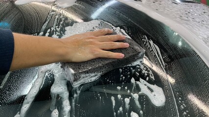 Active contactless foam auto shampoo on the car at the car wash washes the washer