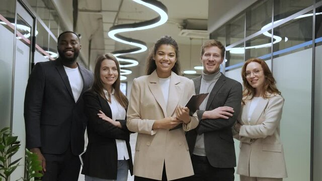 standing in row smiling diverse team posing differently looking at camera. Happy young multiethnic corporate staff