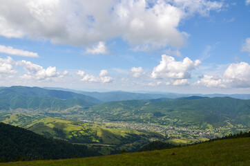 Fototapeta na wymiar Beautiful view from the mountain ridge to the village in the valley near Carpathian mountains at the summer day. Ukraine