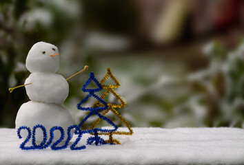 The number 2022 of blue tinsel stands against the background of a snowman and two Christmas trees of tinsel of yellow and blue. New Year,Christmas banner, flyer, layout design, postcard