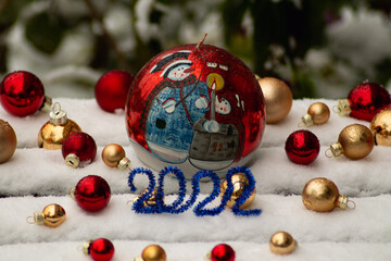 On the snow Christmas tree gold, red balls, a large red candle with the image of snowmen, in front of it is a blue number 2022. Christmas, New Year banner, postcard, flyer, layout design