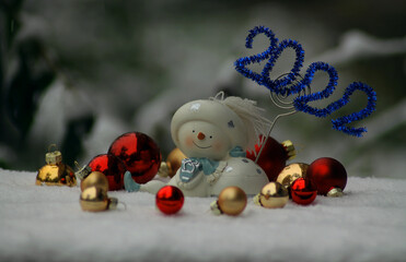 A snowman figure in the snow surrounded by Christmas balls. Christmas, New Year banner, cover, flyer, layout design
