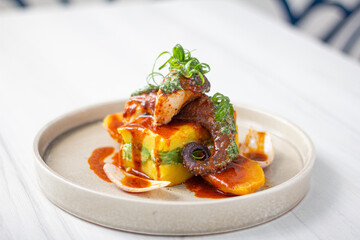 Causa stuffed with tar and avocado, with slices of octopus bathed in sauce.
