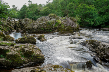 Naklejka na ściany i meble River flowing over rocks in Scotland