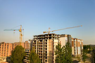 Fototapeta na wymiar High multi storey residential apartment buildings under construction. Concrete and brick framing of high rise housing. Real estate development in urban area.