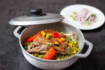 Arroz con pato, a typical Peruvian dish, in a pot on a gray background.
