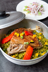Arroz con pato, a typical Peruvian dish, in a pot on a gray background.

