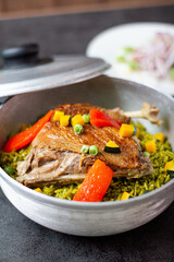 Arroz con pato, a typical Peruvian dish, in a pot on a gray background.
