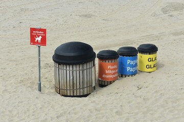 Set of recycling trash containers with glass, paper, plastic and other waste, on Scheveningen beach...