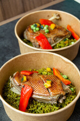 Arroz con pato, a typical Peruvian dish, in a pot on a gray background.
