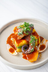 Causa stuffed with tar and avocado, with slices of octopus bathed in sauce.
