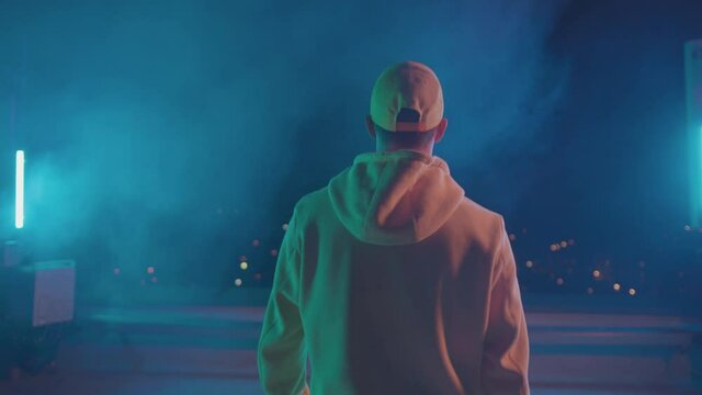 B-boy charismatic dancer walking on night stage rooftop outside before battle performance. Dancing people. Hip hop guy.
