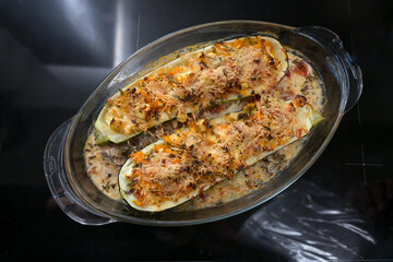 Oven baked zucchini stuffed with vegetables, feta cheese and parmesan in a glass casserole, healthy...