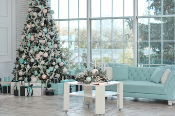 Christmas room with a Christmas tree beautifully decorated, a table and a Christmas composition on the table, a sofa by the window.