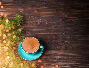 Christmas background. Blue cup and saucer, fir branches on a wooden background. Defocus.