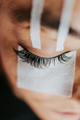 Extreme close up shot of eyelash extension procedure. Cosmetics and body care concept. Shallow depth of field and selective focus.