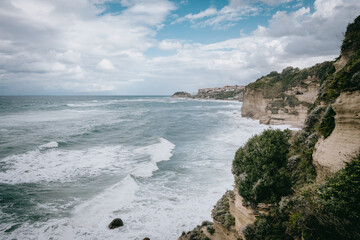 Blick auf Tropea von der Felsküste aus bei tosender Brandung mit der Wallfahrtskirche Santa Maria dell'Isola im Hintergrund, Kalabrien, Italien