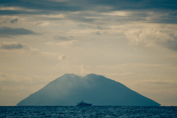 Fernblick zur Vulkaninsel Stromboli mit einem Schiff im Vordergrund, Tropea, Kalabrien, Italien