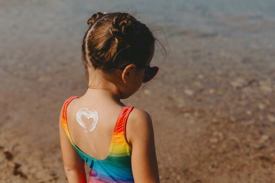 Little girl with heart shaped sunscreen on her back.