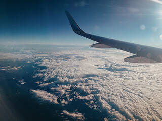 Fototapeta premium Ausblick durch ein Flugzeugfenster auf den Wolkenhimmel - Blaue Stunde