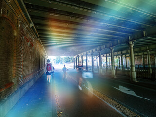 Light effect over Silhouettes of mother and child unrecognizable people on while fast motion under bridge with nearby sightseeing woman