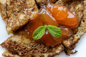 Golden pear jam slices on a toasted pancake with a sprig of mint. Close-up. Delicious homemade dessert.