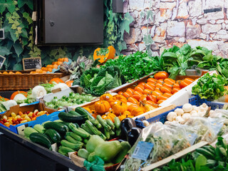 Vegetables for sale at the market counter in supermarket vegetables section - diverse types of salads, tomatoes, champignons, courgettes