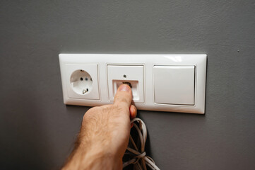 Male hand inserting in wall socket outlet RJ45 internet cable ethernet gigabit lan network...