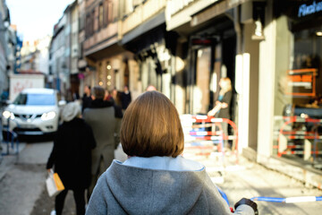 Rear view of people walking on the street being repaired in city center of Strasbourg - French Alsatian architecture defocused in background