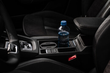 Cup holders inside modern car interior. Interior view of modern car. Bottle placed on the car cup holder.